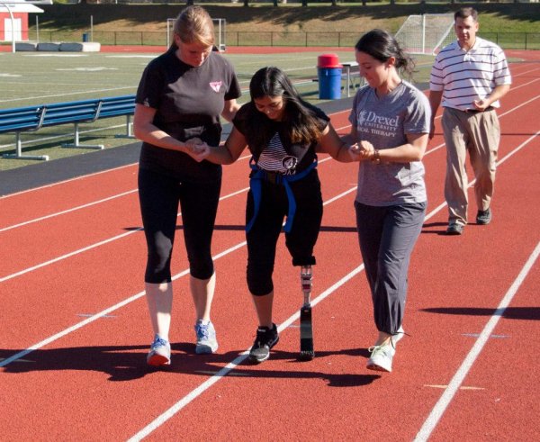 Sophie walking on a track with support